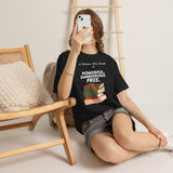 Woman sitting with phone wearing A Woman Who Reads Is Powerful Dangerous and Free feminist T-shirt