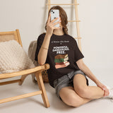 Woman sitting on the phone wearing brown feminist T-shirt with white text and A Woman Who Reads Is Powerful Dangerous and Free book design